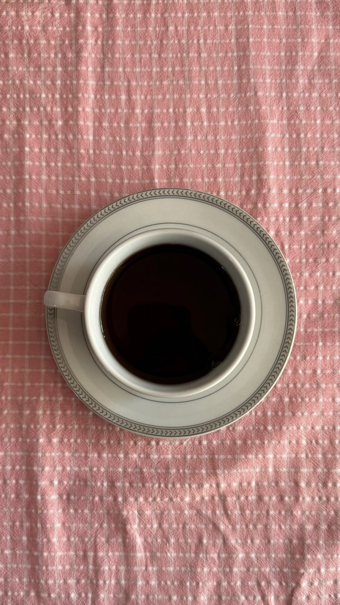 Taza de café sobre un mantel rosa de cuadros