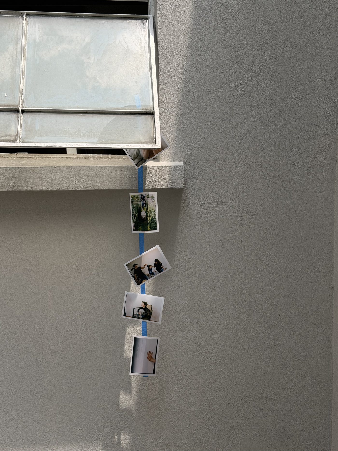 Fotografías pegadas con cinta azul en un muro