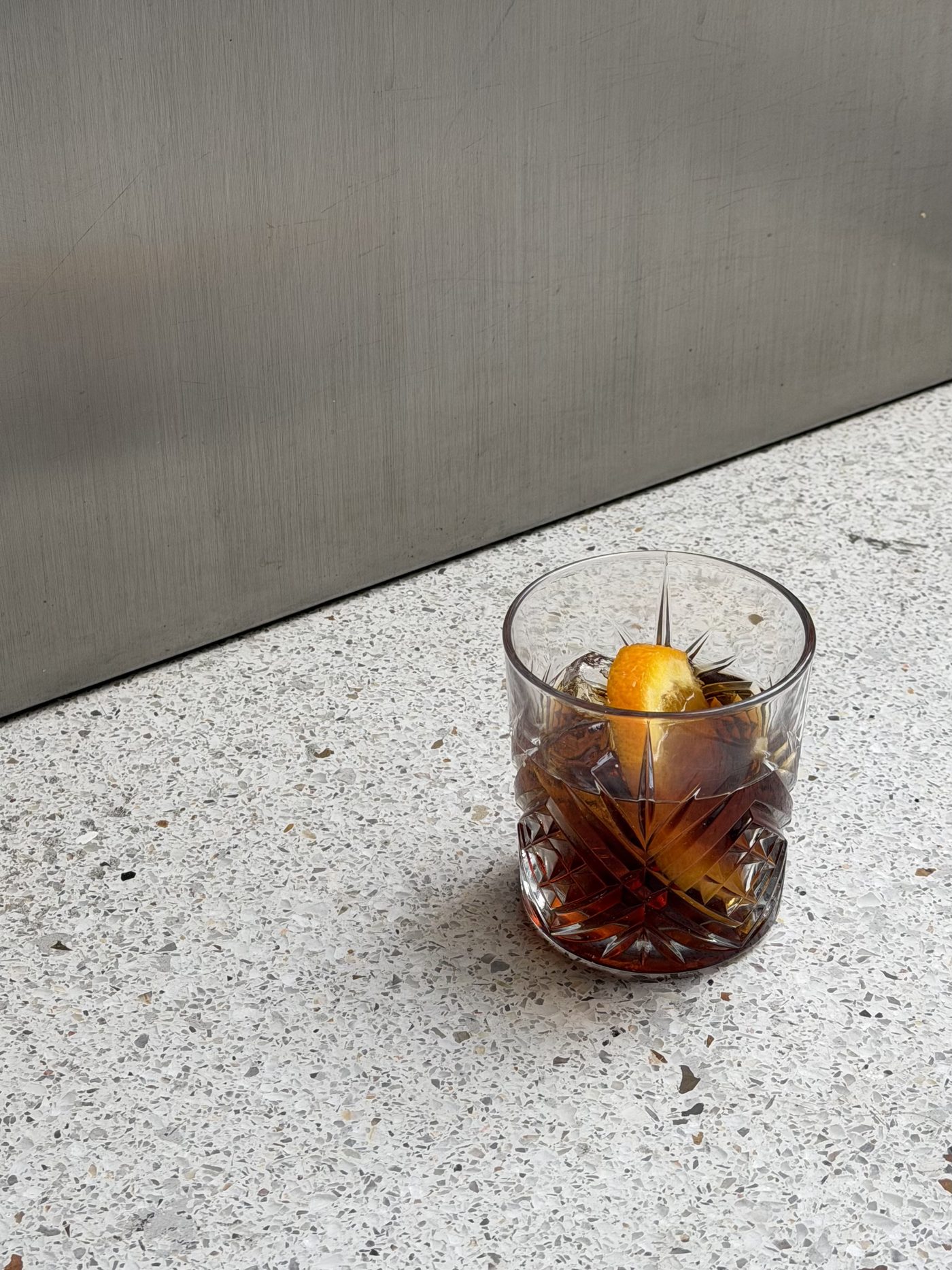 Vaso con hielo y cáscara de naranja sobre una barra